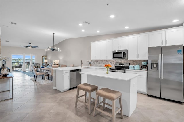 kitchen with appliances with stainless steel finishes, kitchen peninsula, a kitchen island, pendant lighting, and lofted ceiling