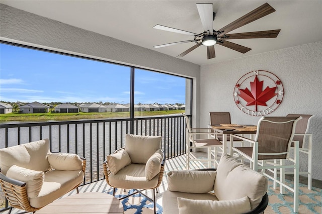 sunroom featuring ceiling fan and a water view