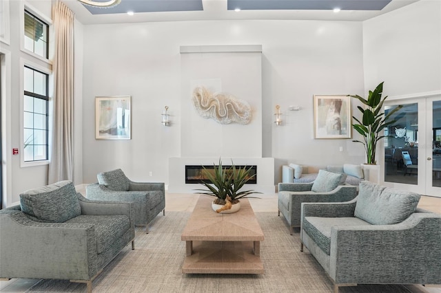 living area with french doors, a glass covered fireplace, and a high ceiling