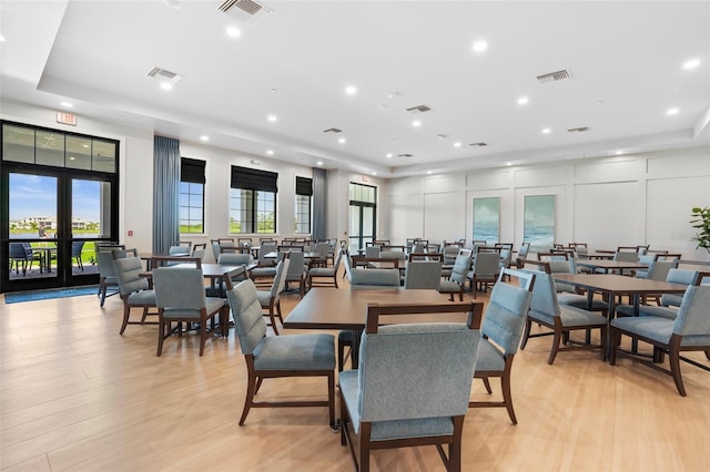 dining space featuring visible vents, a decorative wall, and light wood-style flooring