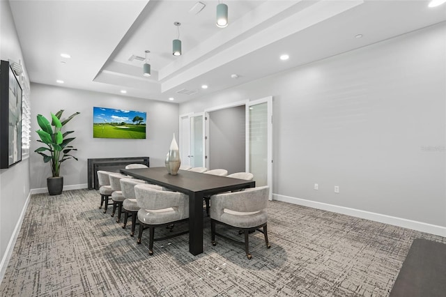 carpeted dining space with baseboards, a raised ceiling, and recessed lighting