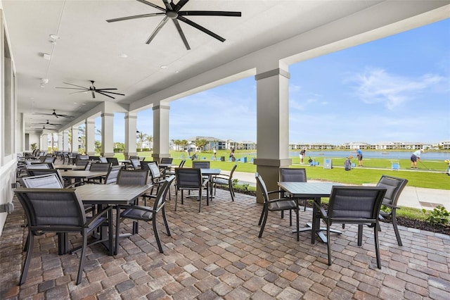 view of patio featuring a water view, ceiling fan, and outdoor dining space