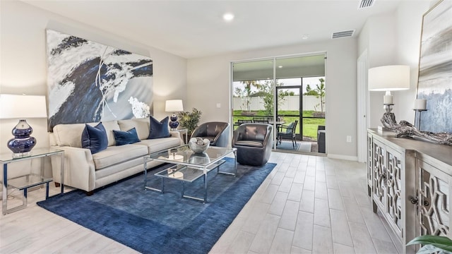 living room featuring light wood-type flooring, baseboards, and visible vents