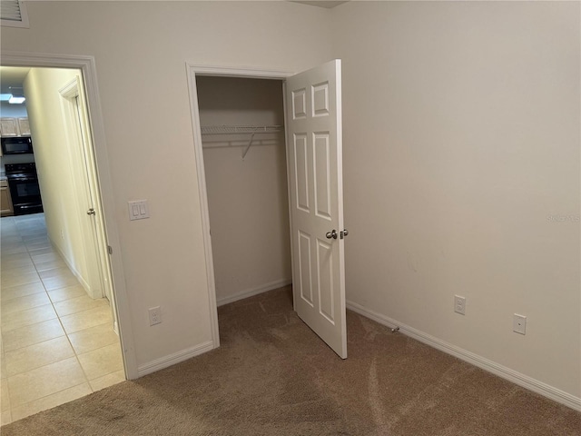 unfurnished bedroom with a closet and light colored carpet