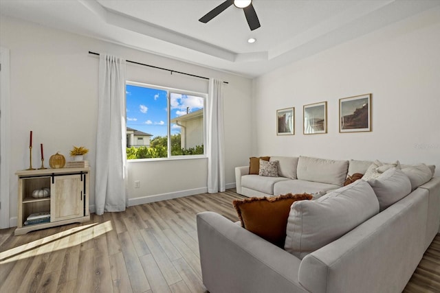 living room with ceiling fan, a raised ceiling, and hardwood / wood-style floors