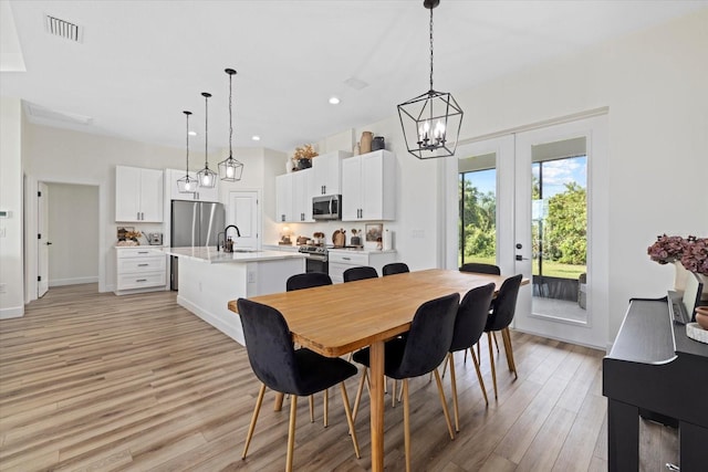 dining room with sink, light hardwood / wood-style flooring, and french doors