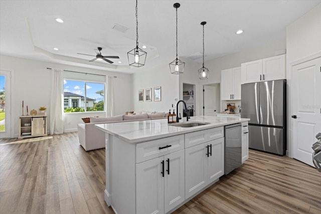 kitchen featuring sink, a center island with sink, white cabinetry, stainless steel appliances, and light hardwood / wood-style floors