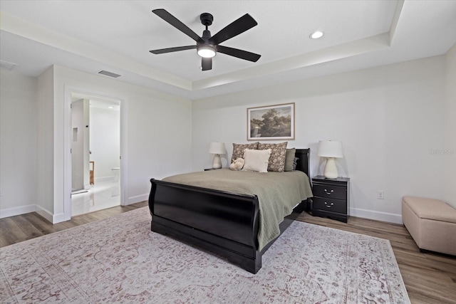 bedroom featuring ceiling fan, hardwood / wood-style flooring, and a tray ceiling