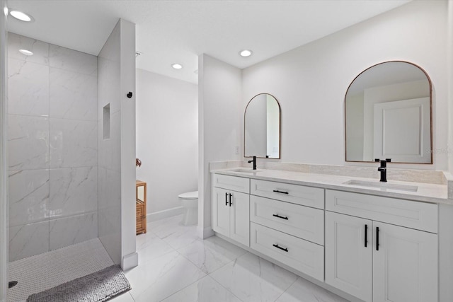 bathroom with a tile shower, vanity, and toilet