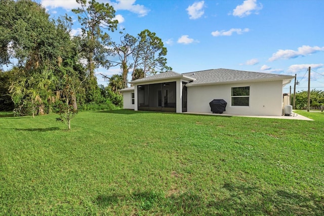 rear view of property featuring a sunroom and a lawn