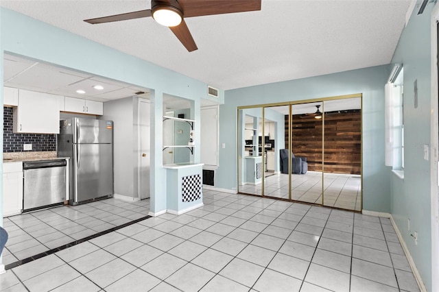 kitchen with appliances with stainless steel finishes, a textured ceiling, decorative backsplash, and white cabinets