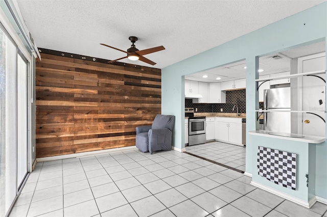 kitchen featuring wooden walls, appliances with stainless steel finishes, white cabinetry, and tasteful backsplash