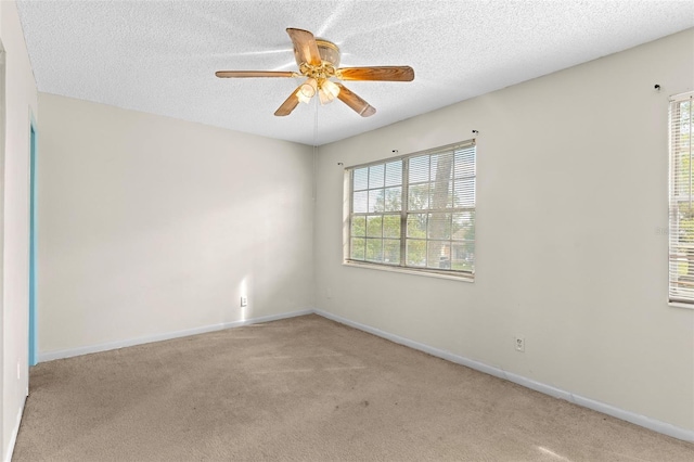 empty room featuring light carpet, a textured ceiling, a healthy amount of sunlight, and ceiling fan