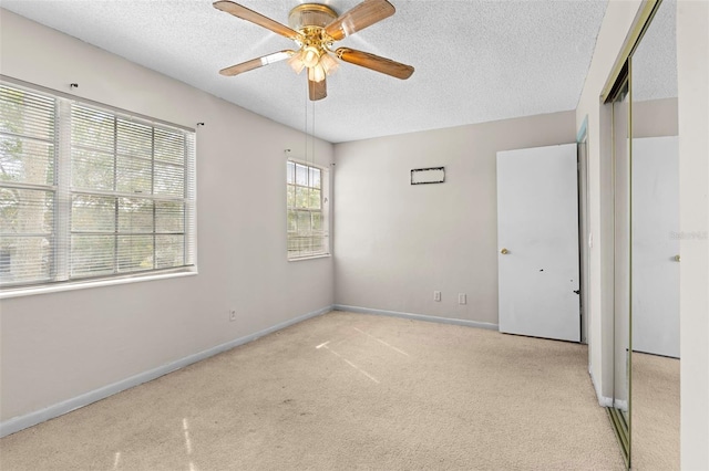 unfurnished bedroom featuring a textured ceiling, light colored carpet, a closet, and ceiling fan