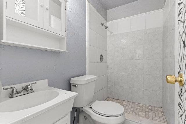 bathroom with vanity, tiled shower, and toilet