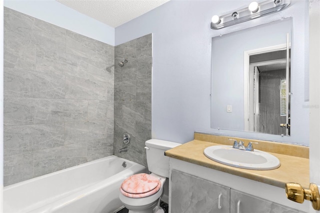 full bathroom with vanity, toilet, tiled shower / bath combo, and a textured ceiling