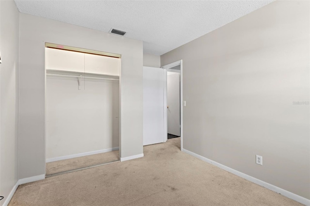 unfurnished bedroom with a closet, a textured ceiling, and light colored carpet