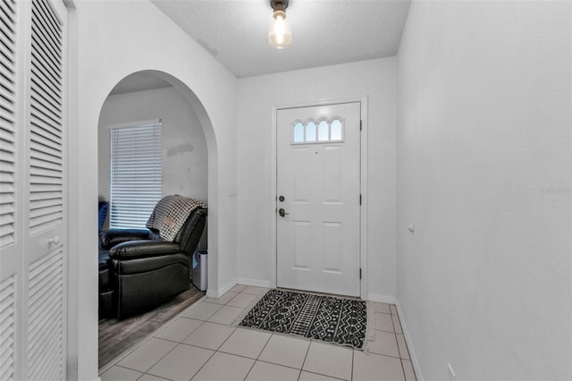 entryway with light tile patterned flooring and a textured ceiling