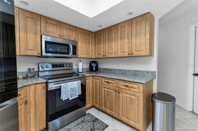 kitchen featuring light stone countertops, light tile patterned floors, and stainless steel appliances