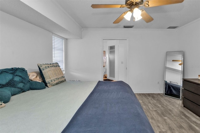 bedroom with ceiling fan, ornamental molding, a textured ceiling, and hardwood / wood-style flooring