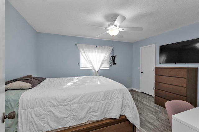 bedroom with ceiling fan, a textured ceiling, and hardwood / wood-style flooring