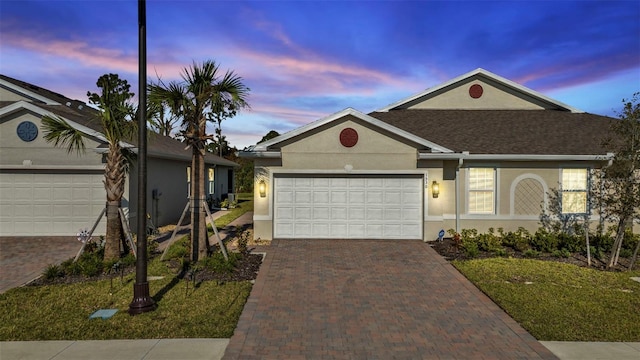 single story home with a garage, stucco siding, and decorative driveway