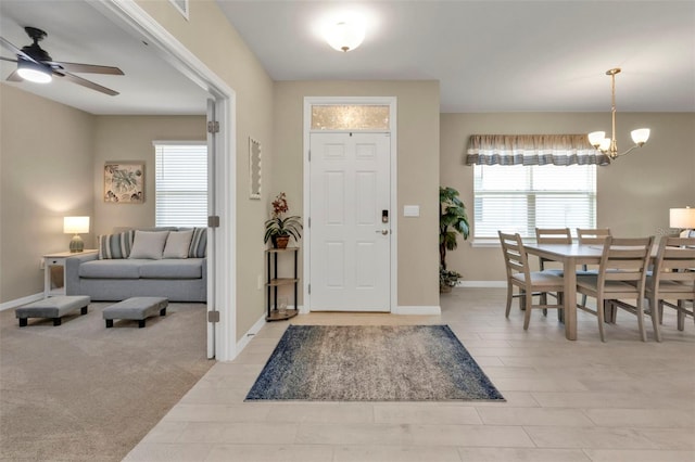 carpeted entryway featuring ceiling fan with notable chandelier