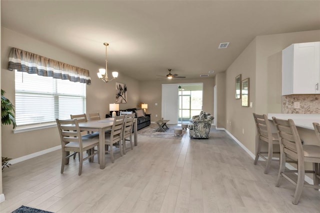 dining area with ceiling fan with notable chandelier and light hardwood / wood-style floors