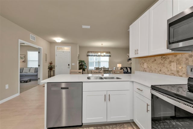 kitchen with white cabinets, sink, kitchen peninsula, light hardwood / wood-style flooring, and stainless steel appliances