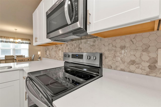 kitchen with pendant lighting, backsplash, stainless steel appliances, and white cabinets