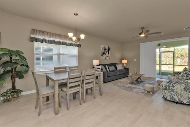 dining room with ceiling fan with notable chandelier and light hardwood / wood-style floors