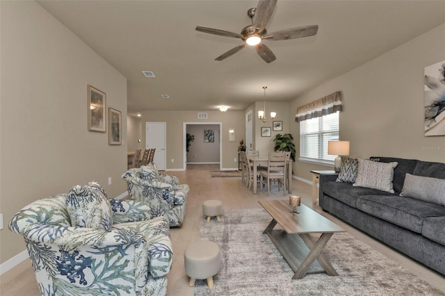 living room featuring ceiling fan with notable chandelier and light hardwood / wood-style flooring