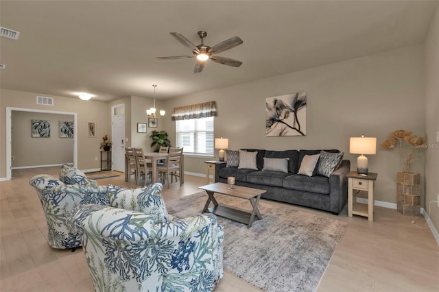 living room with ceiling fan with notable chandelier and light wood-type flooring