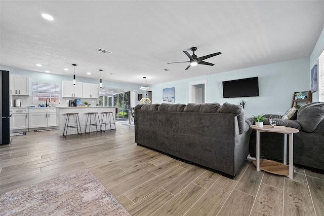 living room featuring ceiling fan and light wood-type flooring