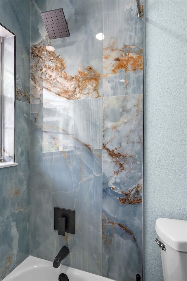 bathroom with tiled shower / bath and toilet