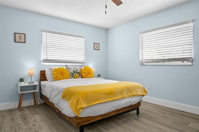 bedroom with ceiling fan, multiple windows, and dark wood-type flooring