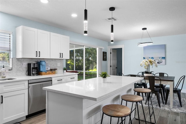 kitchen featuring pendant lighting, white cabinets, dishwasher, and a kitchen island