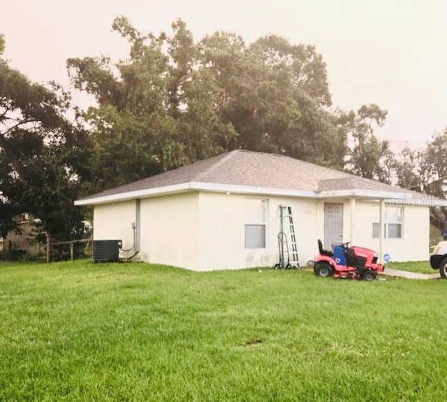 rear view of property featuring a lawn and central air condition unit