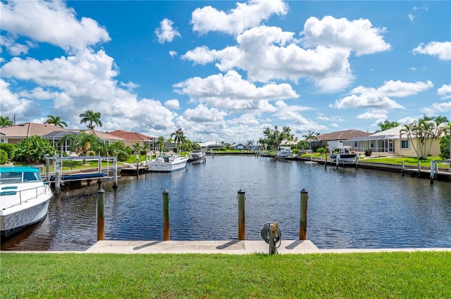 dock area with a lawn, a water view, and glass enclosure