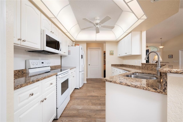 kitchen with light hardwood / wood-style floors, white cabinetry, dark stone countertops, and white appliances