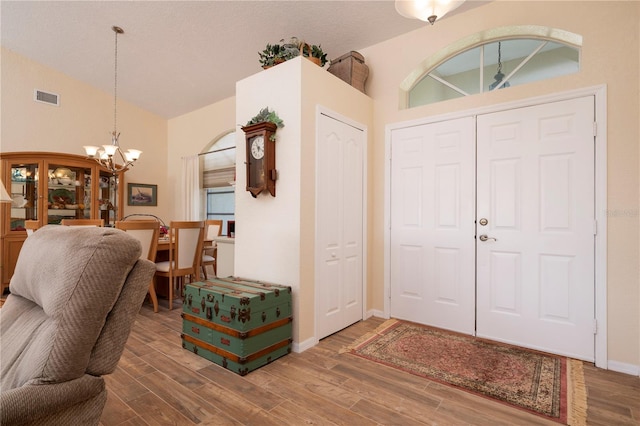 entrance foyer featuring high vaulted ceiling, a notable chandelier, and wood-type flooring