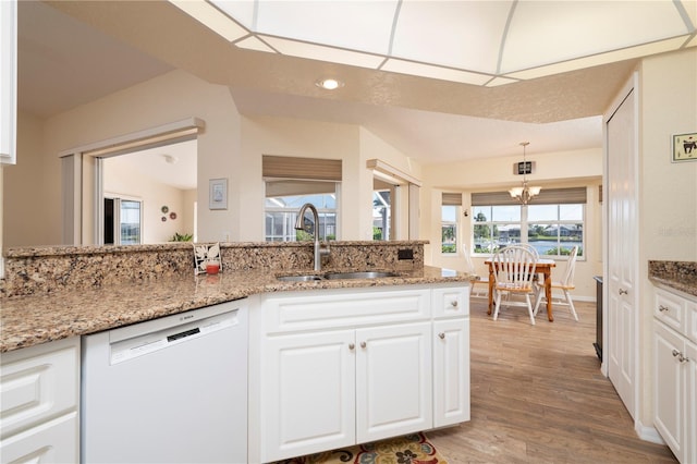 kitchen with dishwasher, decorative light fixtures, white cabinetry, light stone counters, and light hardwood / wood-style floors