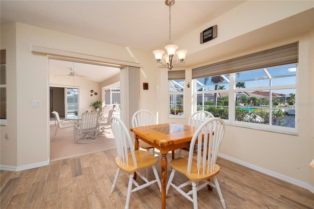 dining space featuring light hardwood / wood-style flooring, a healthy amount of sunlight, lofted ceiling, and ceiling fan with notable chandelier