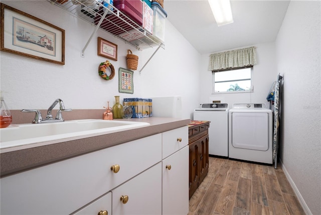 washroom featuring cabinets, hardwood / wood-style floors, sink, and washer and clothes dryer