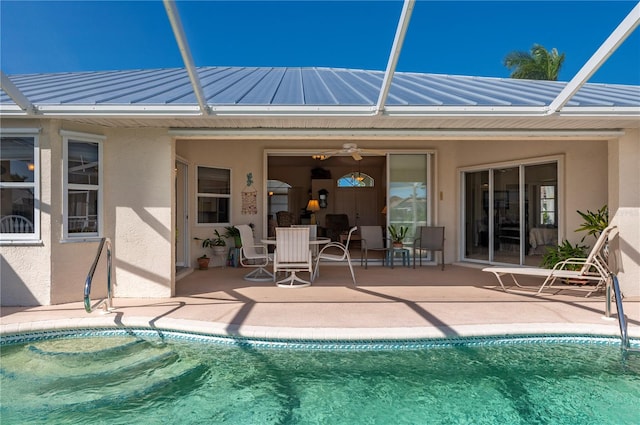 view of swimming pool featuring a patio area, glass enclosure, and ceiling fan