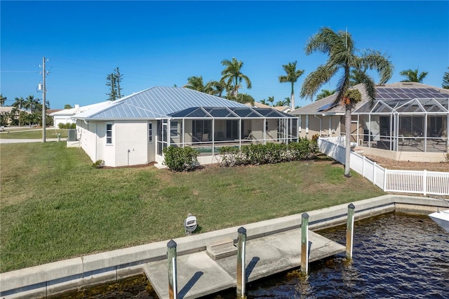 rear view of house featuring a water view, a lanai, and a lawn