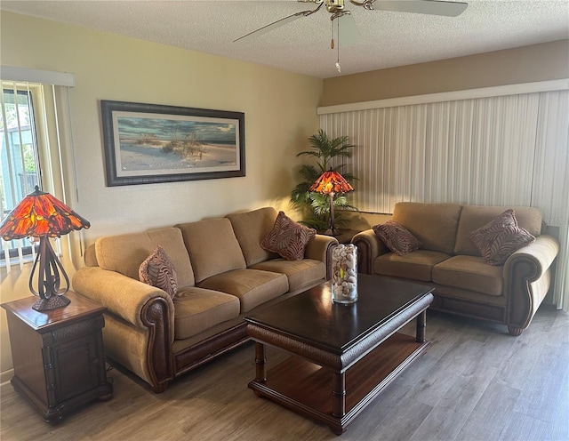 living room featuring ceiling fan, hardwood / wood-style flooring, and a textured ceiling