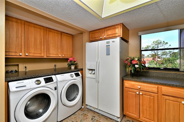 washroom featuring washer and dryer, a textured ceiling, and cabinets