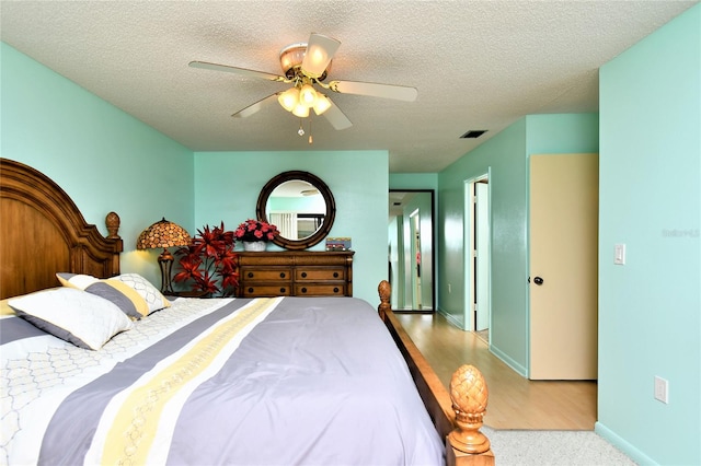 bedroom with a textured ceiling, light wood-type flooring, and ceiling fan