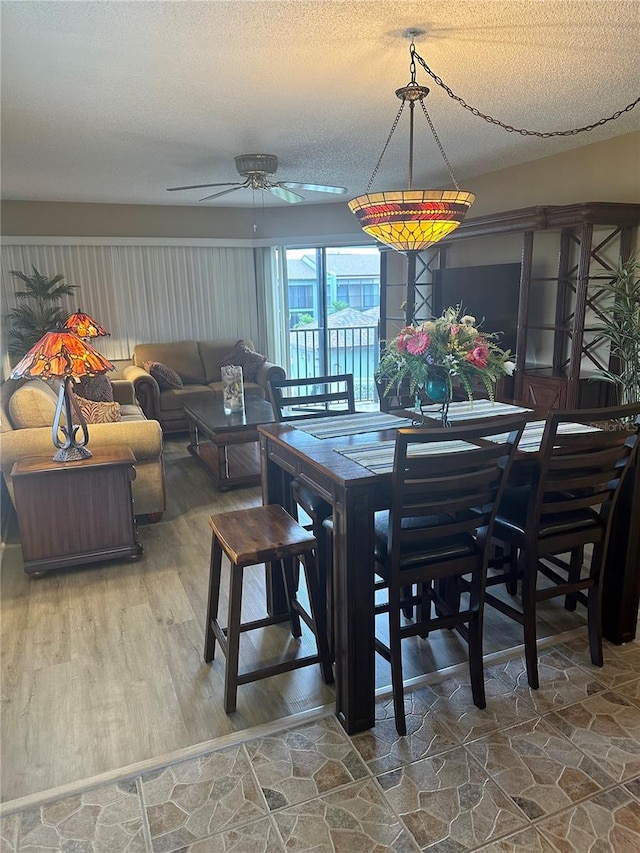 dining room with a textured ceiling, wood-type flooring, and ceiling fan